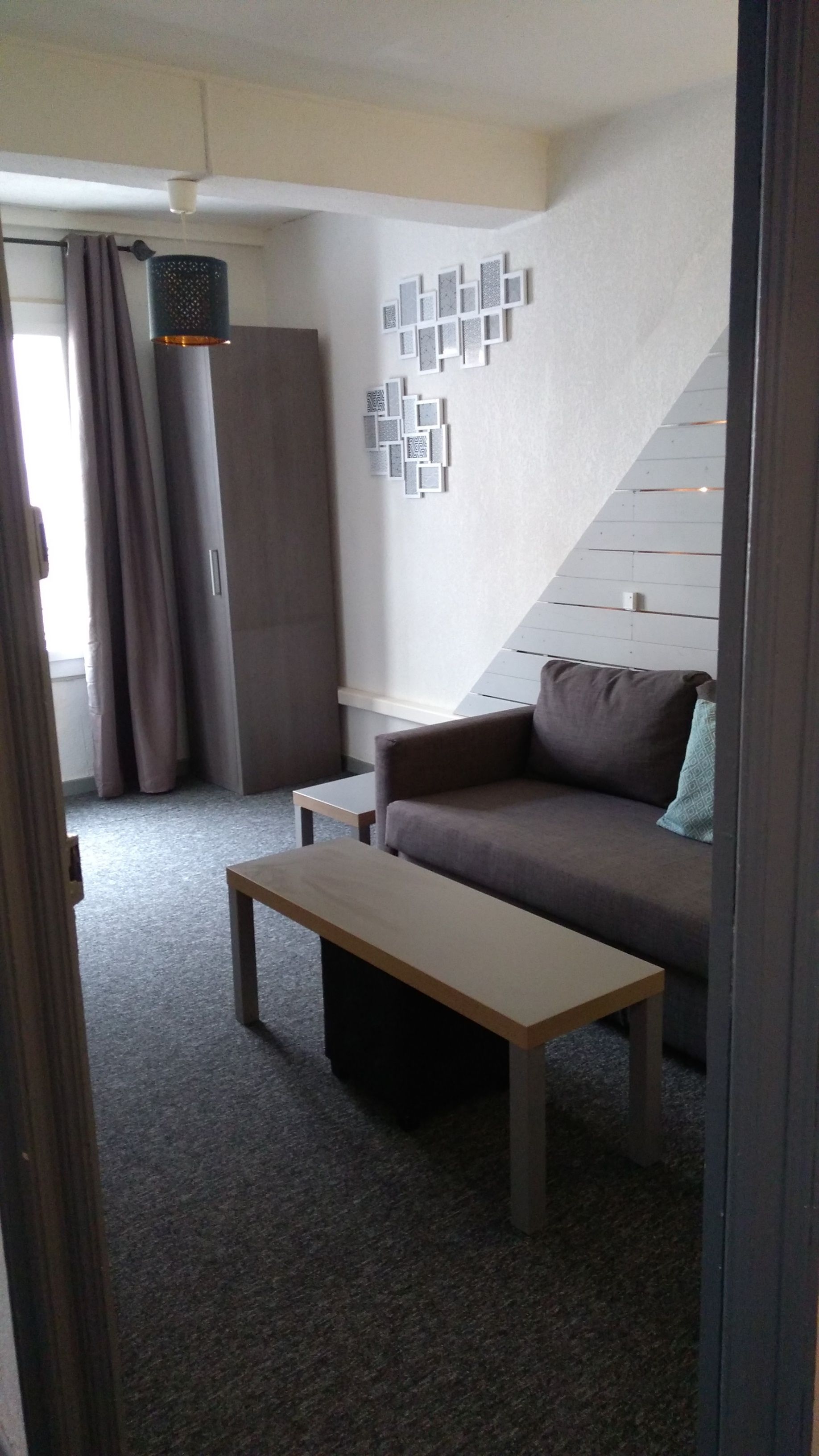 En stue med sofa, sofabord, skab og vægmonteret lampe.