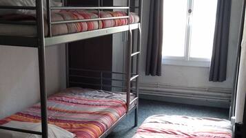 Ein Schlafsaalzimmer mit Etagenbetten, einem Kleiderschrank und einem Fenster mit Vorhängen.