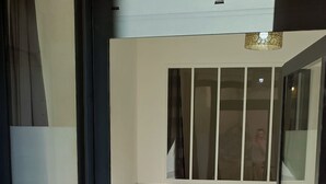A modern room with a glass door, a bench, and a bed with a patterned headboard. - Mauguio Center Hôtel (Mauguio)