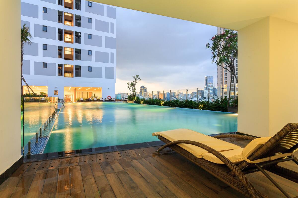 A rooftop pool area with lounge chairs and a view of the city skyline.