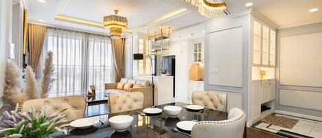 A modern dining area with a glass table, white chairs, and a chandelier.