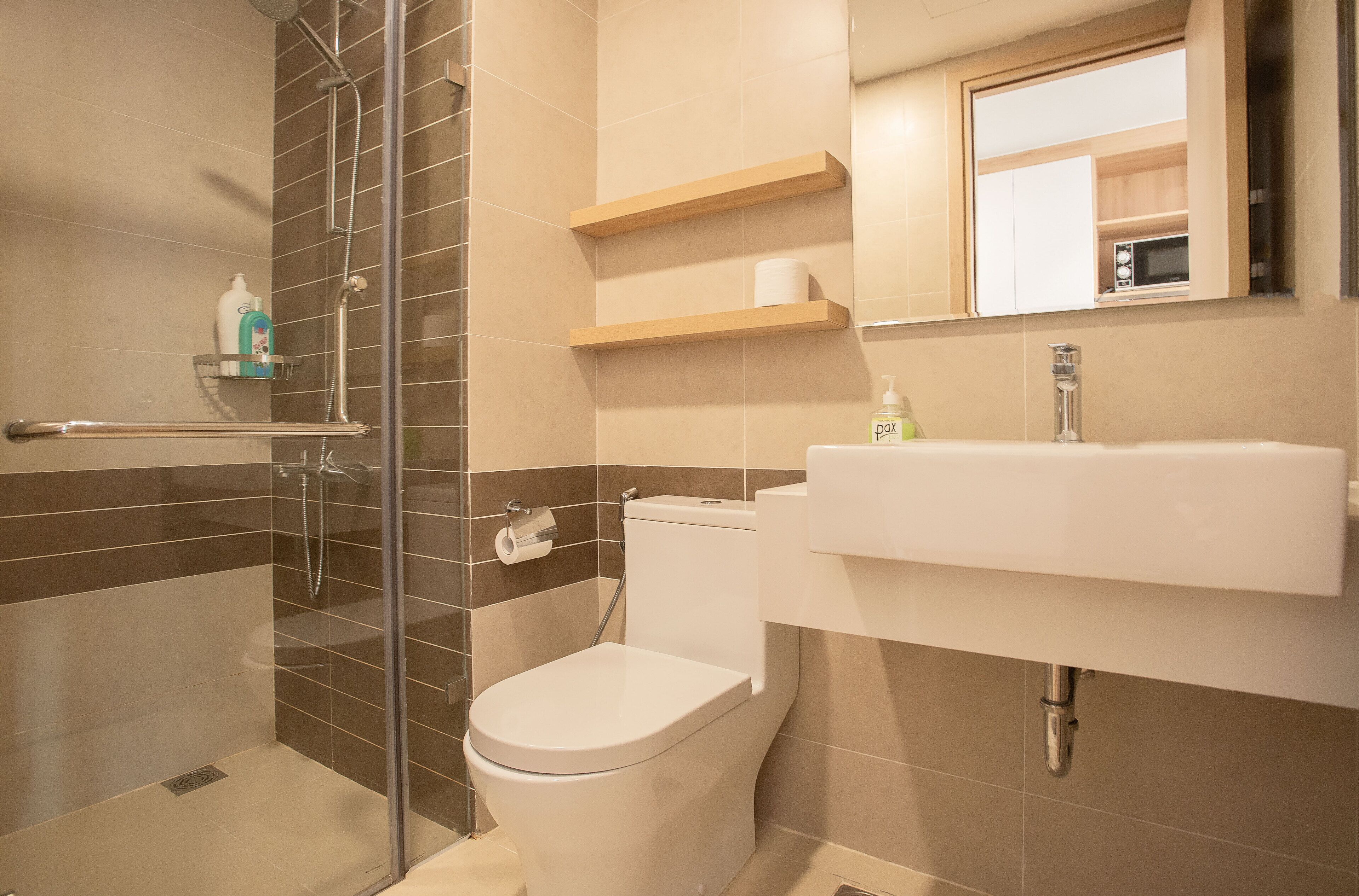 A modern bathroom with a glass-enclosed shower, a toilet, and a sink with a mirror above.