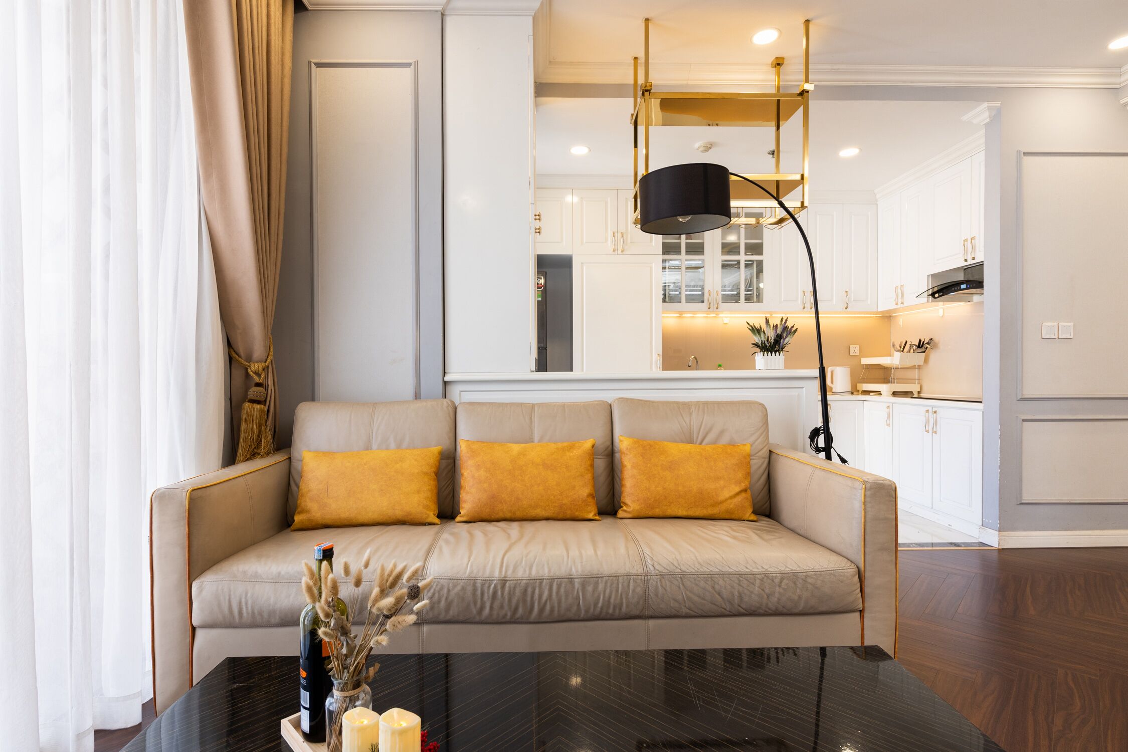 A modern living room with a sofa, a coffee table, and a kitchen in the background.