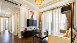 A modern living room with a sofa, a glass coffee table, a TV, and a chandelier. - TeeUP Home (Ho Chi Minh City)
