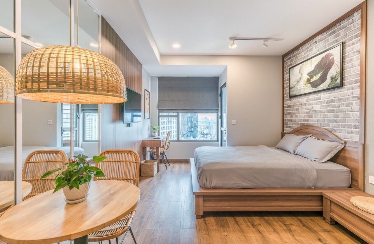 Une chambre moderne avec un grand lit, un coin repas comprenant une table et des chaises, et une vue sur la ville grâce à de grandes fenêtres.