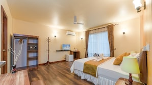 A hotel room with a bed, bedside table, desk, and wardrobe.