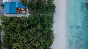 An aerial view of a beach with a building featuring a blue roof and a wooden deck.