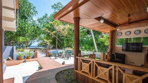 A wooden deck with a pool, outdoor seating, and a TV mounted on the wall.