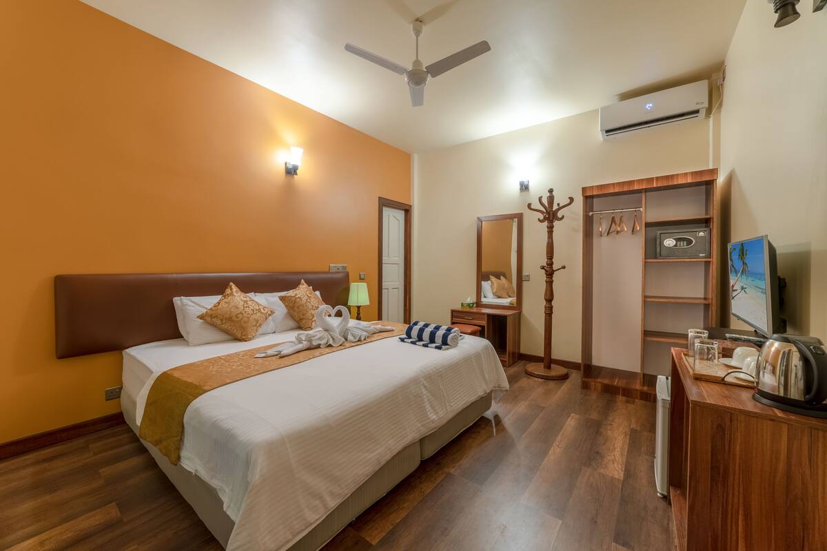 Une chambre d’hôtel avec un grand lit, une armoire, un miroir, une télévision et une machine à café.