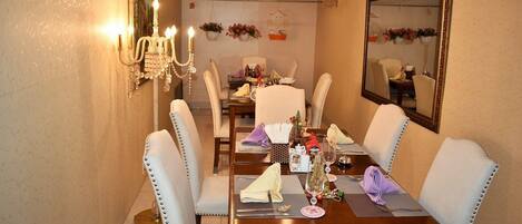 A dining room with a wooden table set for four, surrounded by upholstered chairs with metal studs.