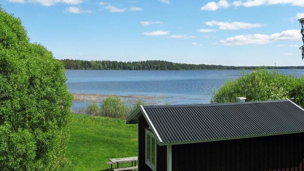 Un chalet au bord du lac offrant une vue sur un lac paisible et une forêt.