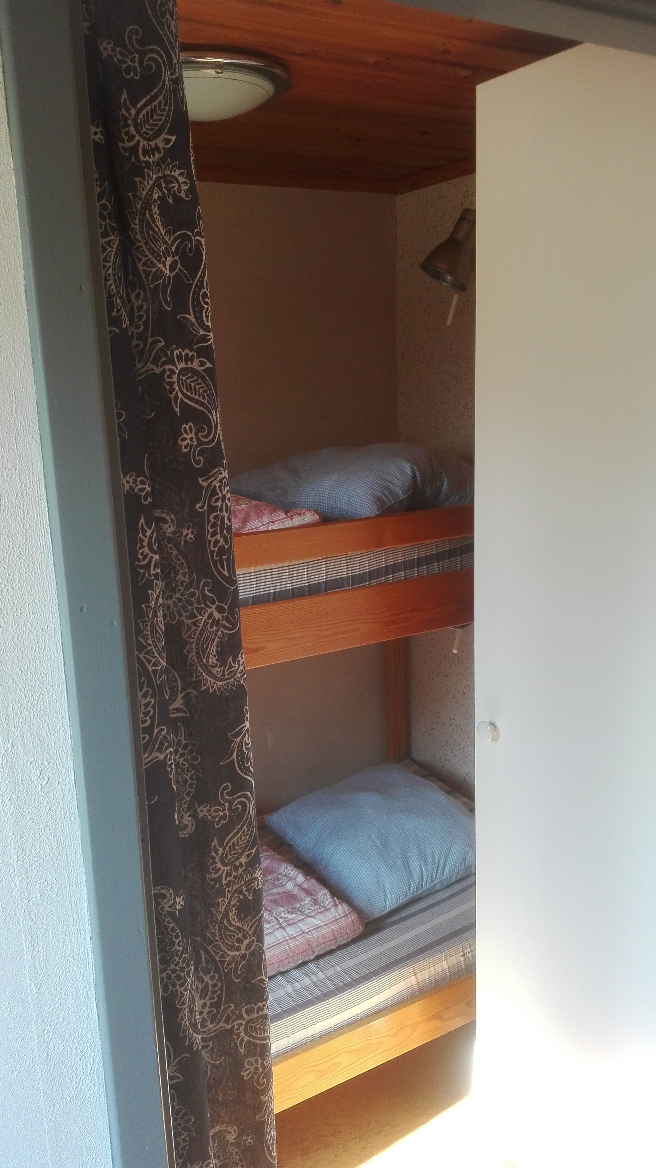 A bunk bed with two levels, each with a pillow and a blanket.