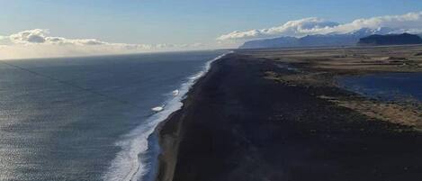 A coastal landscape with a beach and distant mountains.