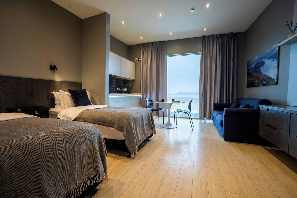 Habitación de hotel con dos camas, una kitchenette pequeña, un comedor y un sofá.