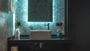 Un baño con pared de mármol, un espejo grande, un lavabo y un perchero para toallas.
