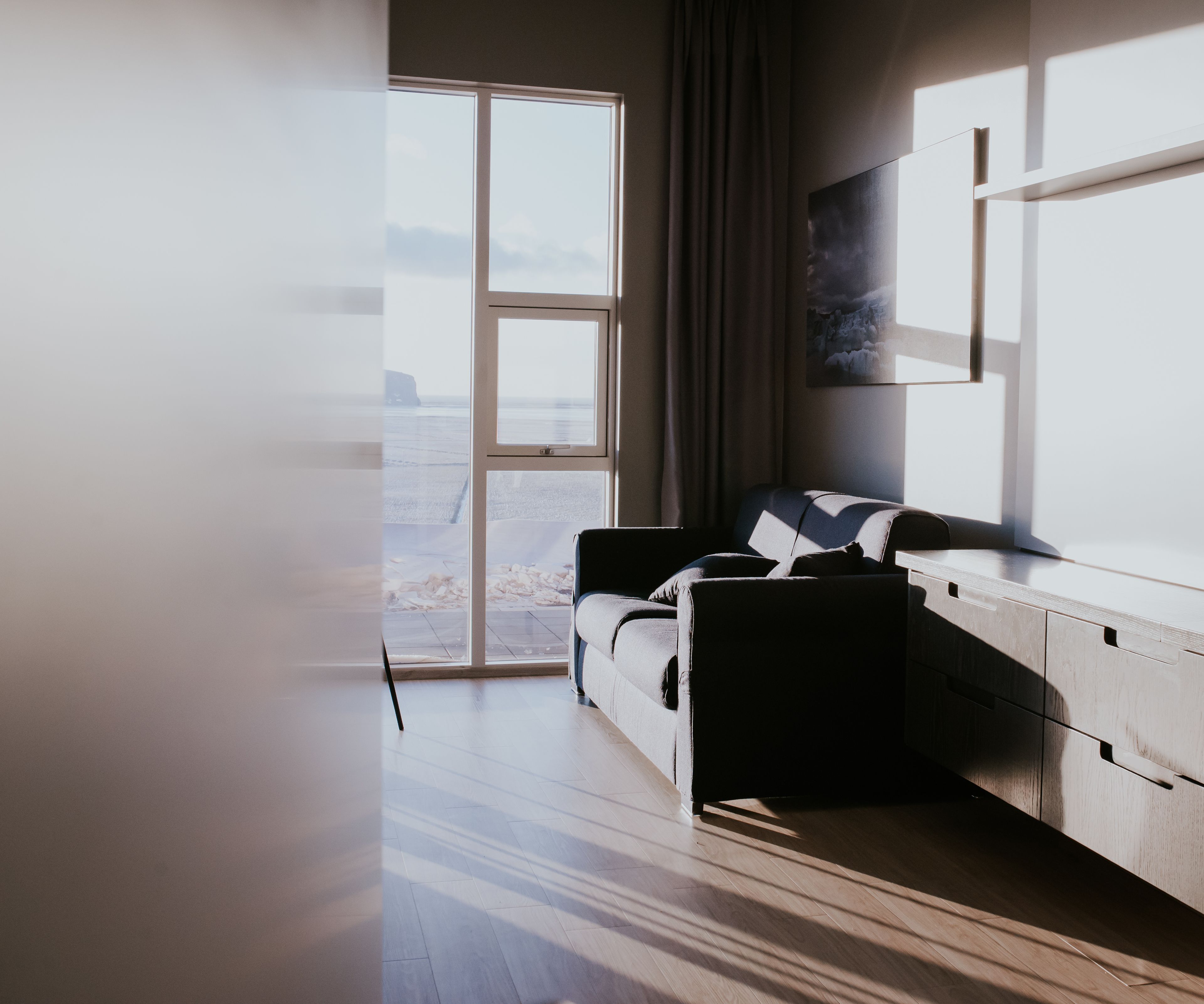 A modern room with a large window, a sofa, and a wooden desk.