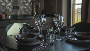 A dining table set with clear glassware and bowls, with a modern kitchen in the background.