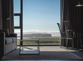 Una habitación moderna con un ventanal grande, un sofá, una mesa de centro y una silla.