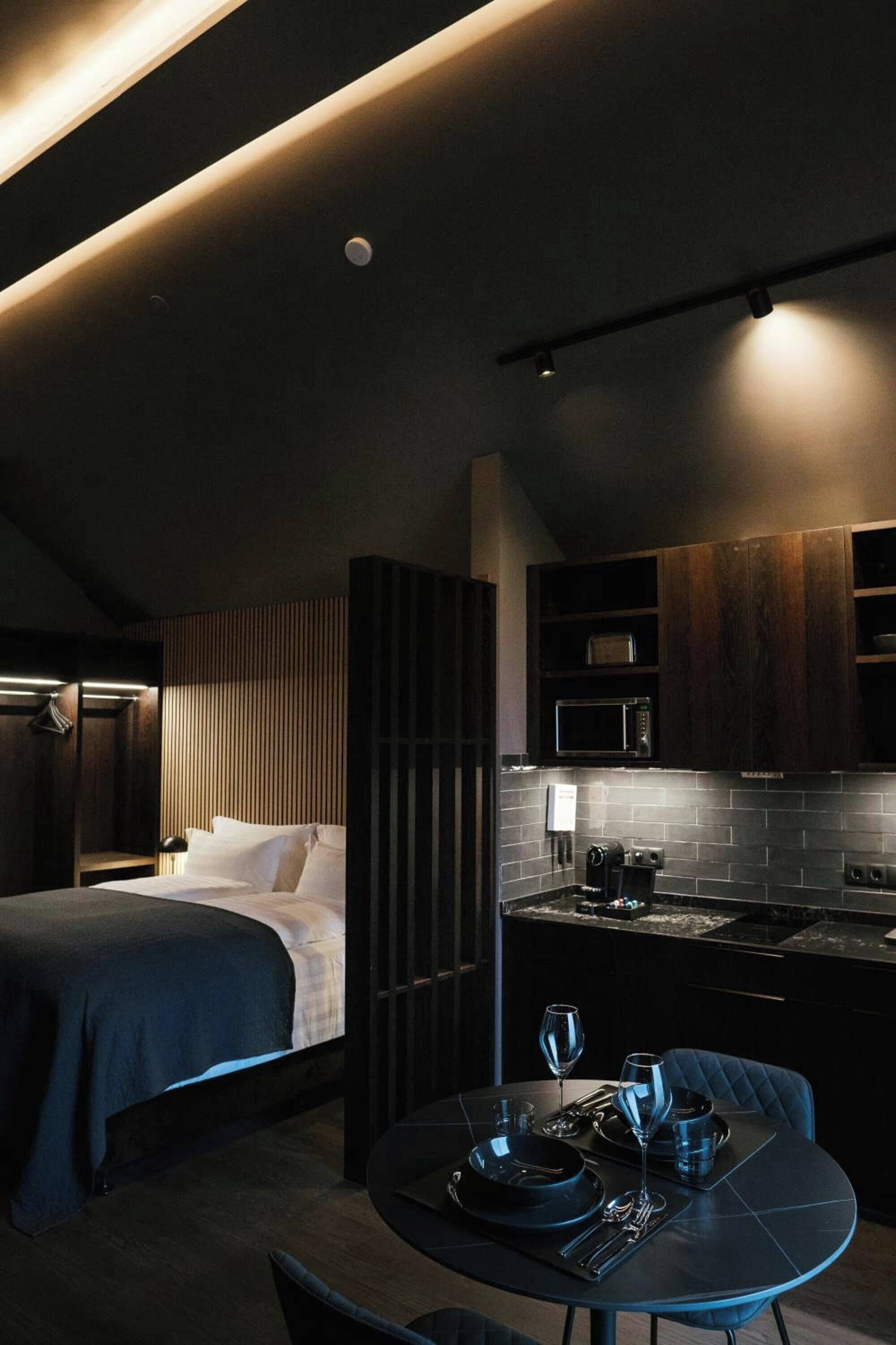 Una habitación de hotel moderna con una cama, una mesa de comedor para dos personas y una kitchenette.
