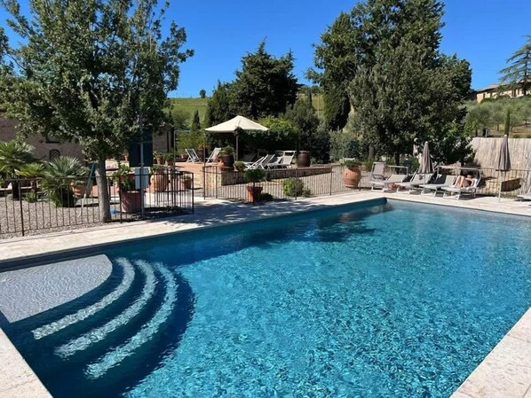 A rectangular swimming pool with clear blue water, surrounded by a fence and lounge chairs. - Rocca degli Olivi (San Gimignano)