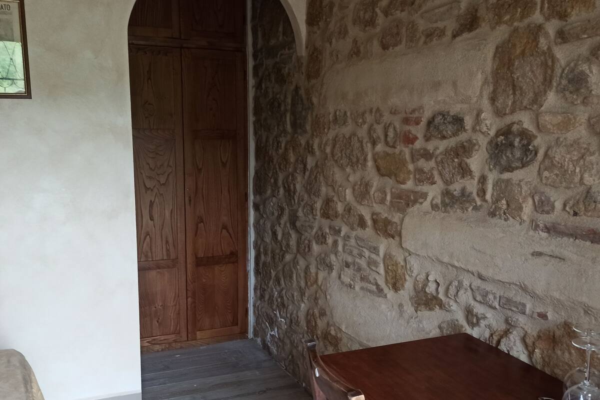 Eine Steinsäule, eine Holztür und ein kleiner Tisch mit Weinflasche und Glas.