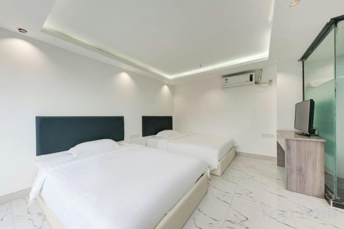 Een hotelkamer met twee bedden, een flatscreen televisie en een klein bureau.