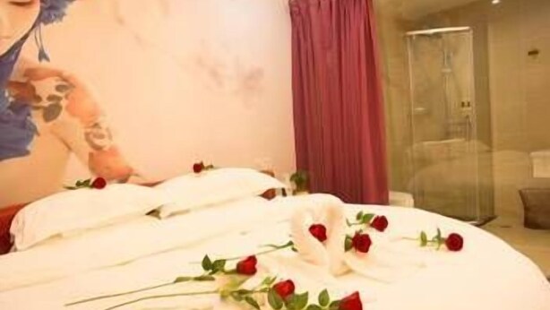 Una habitación de hotel con cama, un mural en la pared y cabina de ducha de vidrio.