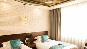 Una habitación de hotel con dos camas, pared de ladrillo, techo de madera y una ventana con cortinas.