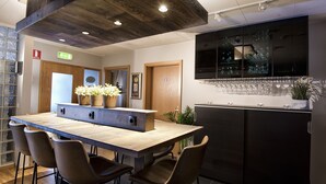 A modern kitchen with a wooden island, black cabinets, and a large TV above the counter. - B14 Hostel (Reykjavik)