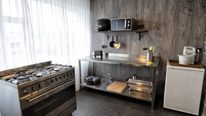 A modern kitchen with a gas stove, oven, microwave, and a small refrigerator. - B14 Hostel (Reykjavik)