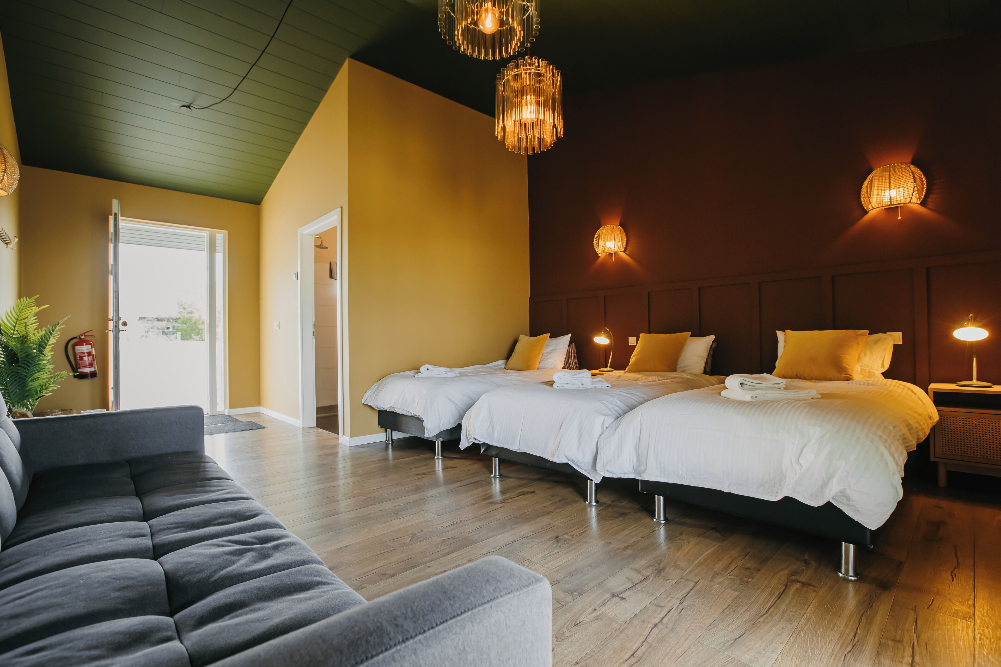 A hotel room with two beds, a sofa, and a small table.