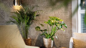 A cozy seating area with a patterned wall, two potted plants, and a modern lamp. - Guesthouse Hill (Hrunamannahreppur)