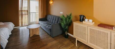 Et hyggeligt værelse med en sofa, et rundt bord, et skab og en potteplante.