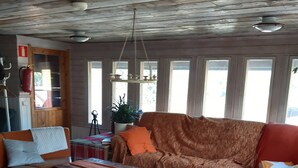 Een gezellige woonkamer met een houten plafond, een bank, een salontafel en een televisie.