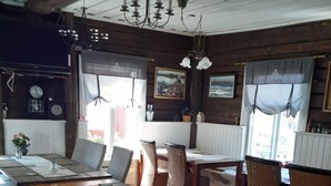 Een rustieke houten eethoek met een lange tafel en banken, omringd door rieten stoelen.