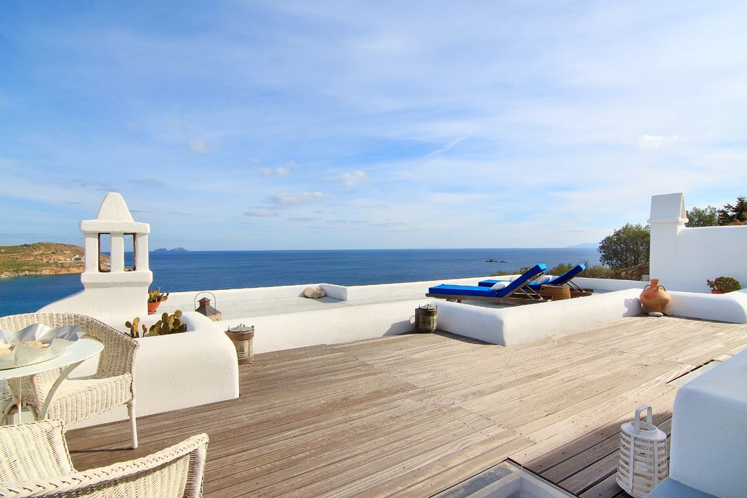 Une terrasse dotée de meubles en osier, d’une terrasse en bois et offrant une vue sur la mer.