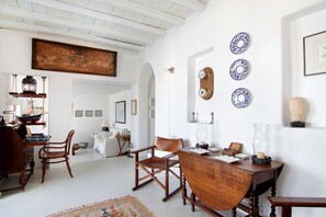 A spacious room with a wooden dining table, chairs, and a large painting on the wall. - Villa Armonia (Mykonos)