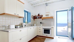 Una cucina con mobili bianchi, forno integrato e una finestra con vista panoramica.
