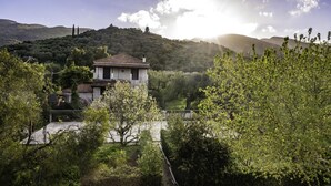 A house with a tiled roof, surrounded by lush greenery and hills in the background. - Zante 5 bedroom Villa with private pool and basketball court (Zakynthos)
