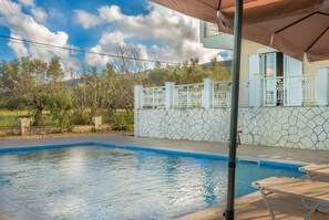 A swimming pool with a tiled edge, a white fence, and a balcony with white railings.
