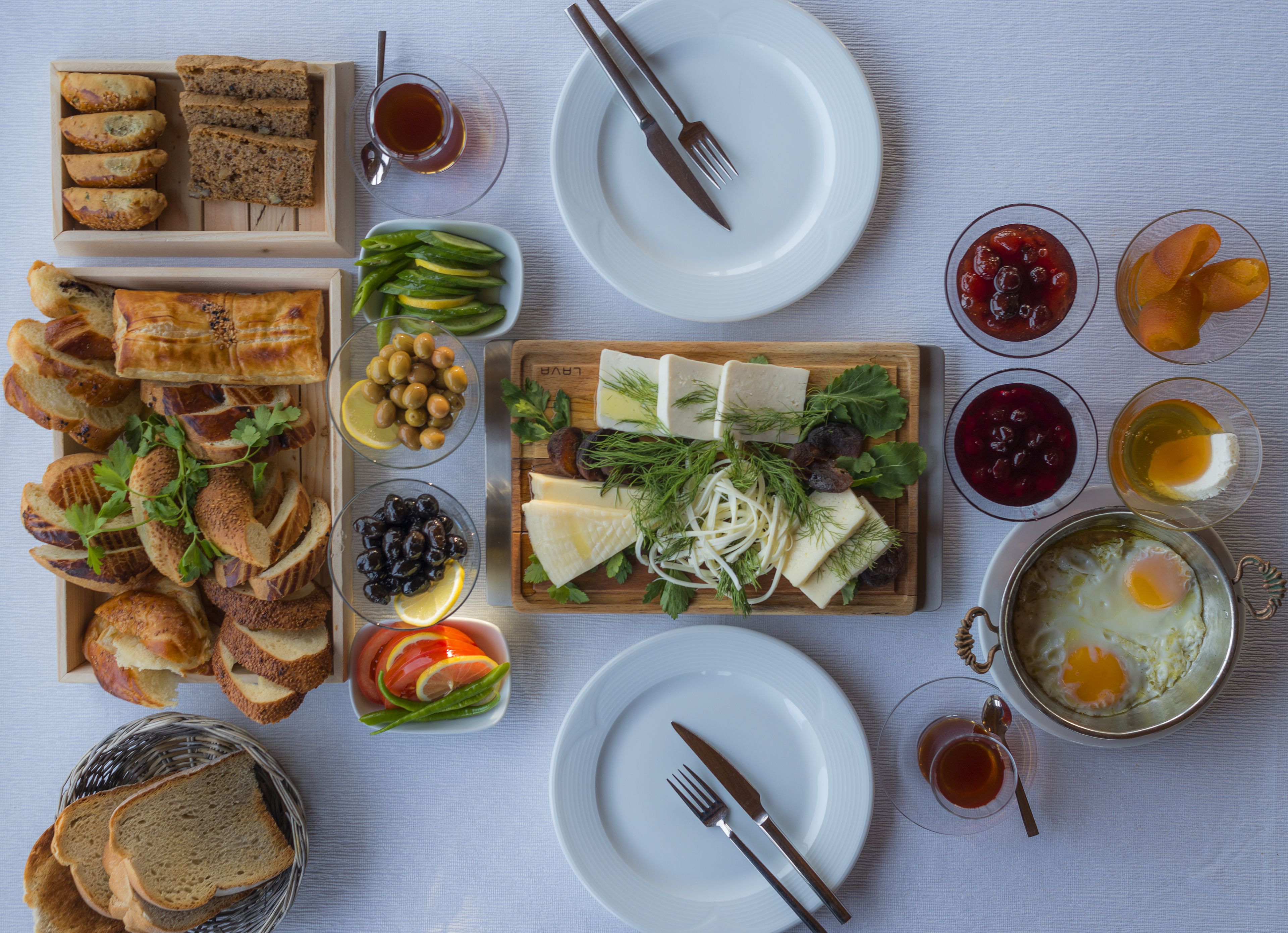 Una bandeja de desayuno con pan, queso, huevos y diversas frutas y verduras.
