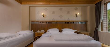 Habitación de hotel con dos camas, suelo de madera, un candelabro y un papel tapiz estampado.