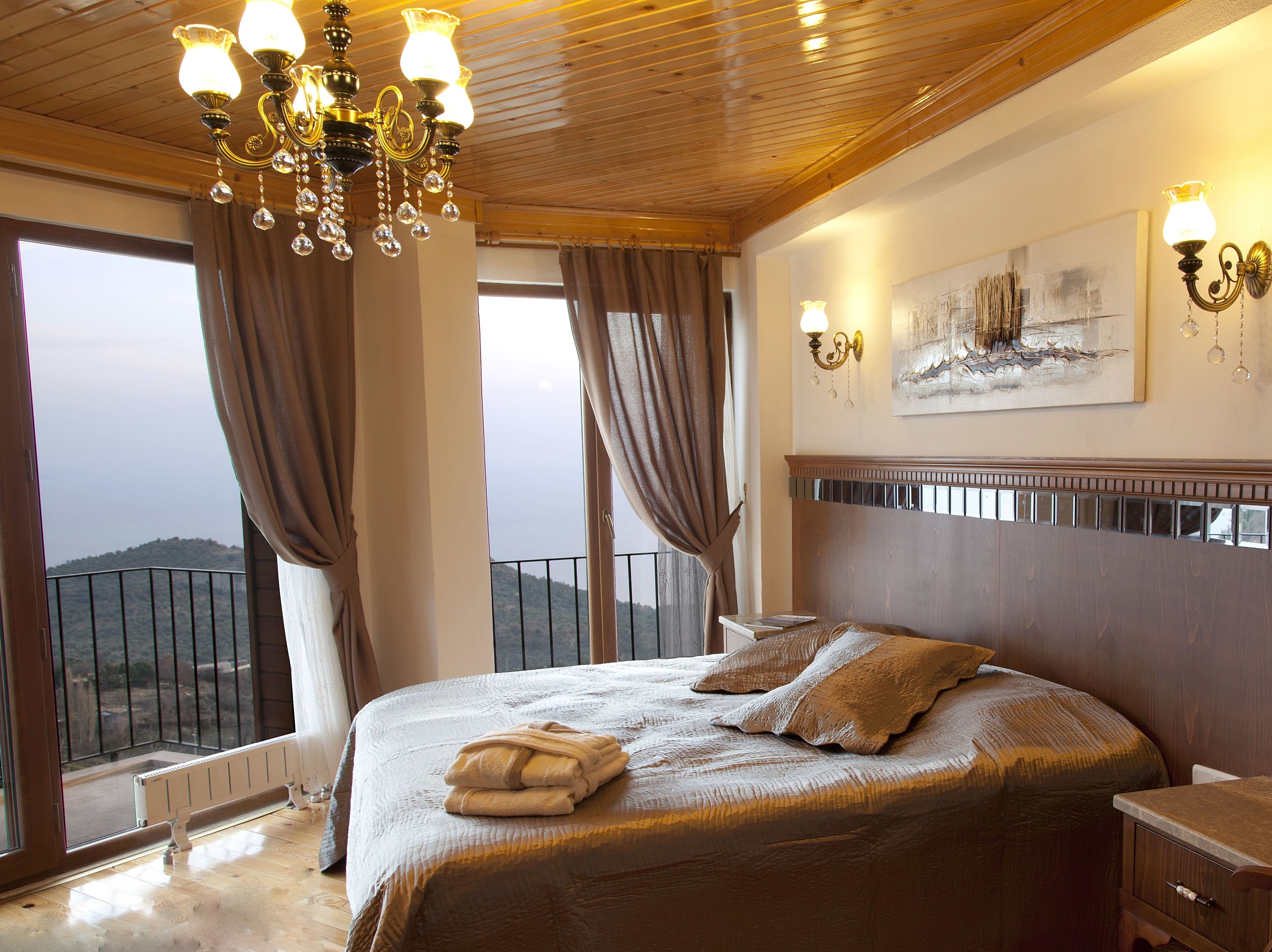 Un dormitorio con una cama grande, una araña, un cuadro y vistas al exterior.