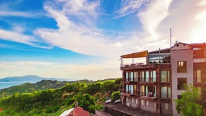 A multi-story building with balconies, large windows, and a view of the surrounding landscape. - Assos Kayalar Terrace Boutique Hotel (Ayvacik)