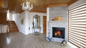 A spacious room with a wooden floor, a fireplace, a chandelier, and a staircase. - Assos Kayalar Terrace Boutique Hotel (Ayvacik)