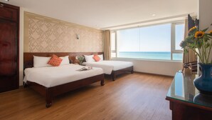 A hotel room with two beds, a wooden floor, a large window with a view of the sea, and a vase with flowers on a table. - Le Soleil Hotel Nha Trang (Nha Trang)