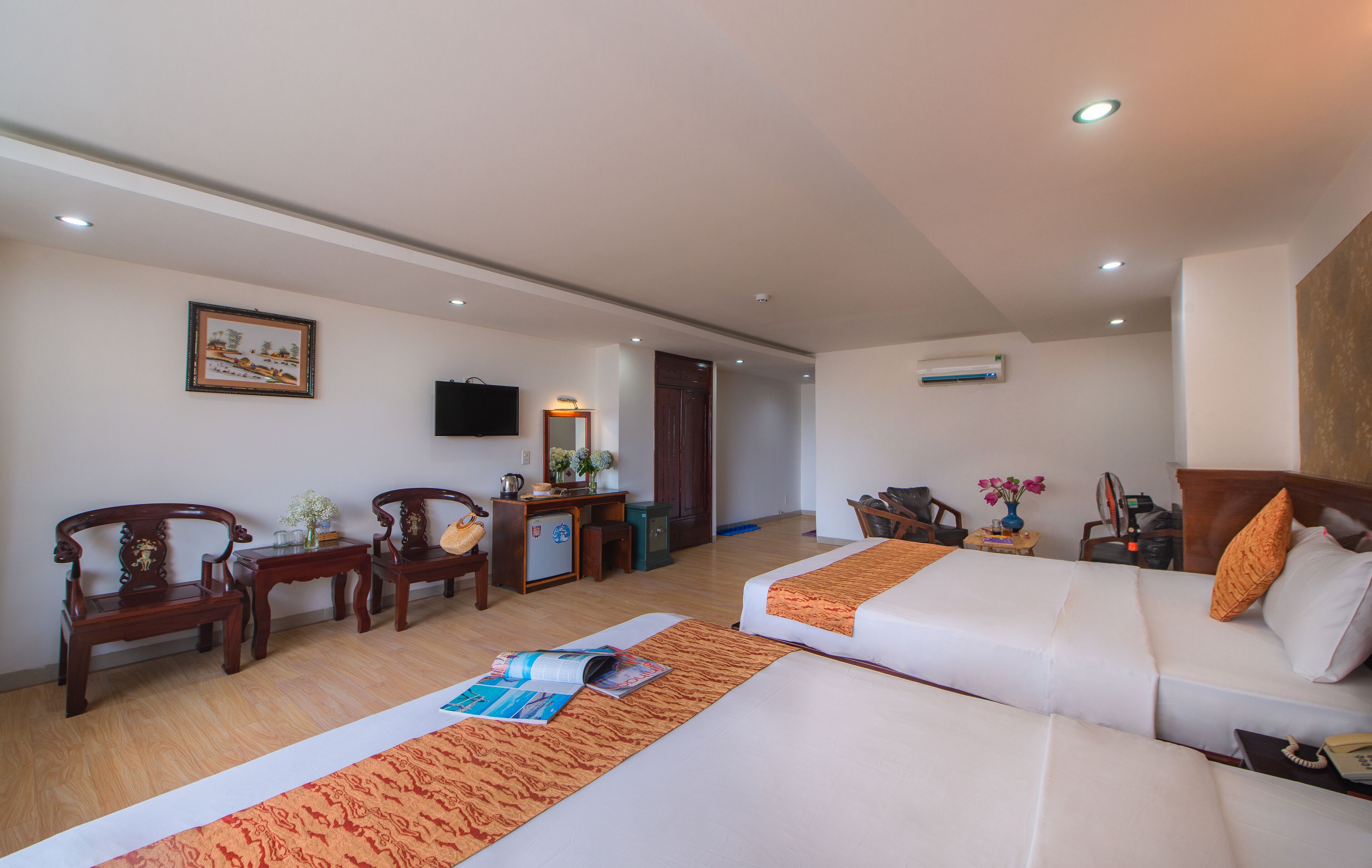A hotel room with two beds, a desk, a chair, a TV, and a door.