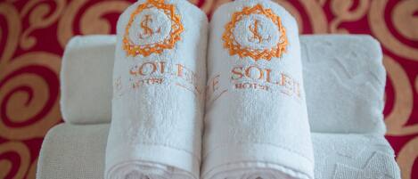 Two neatly folded white towels with embroidered text and a logo, placed on a white towel.