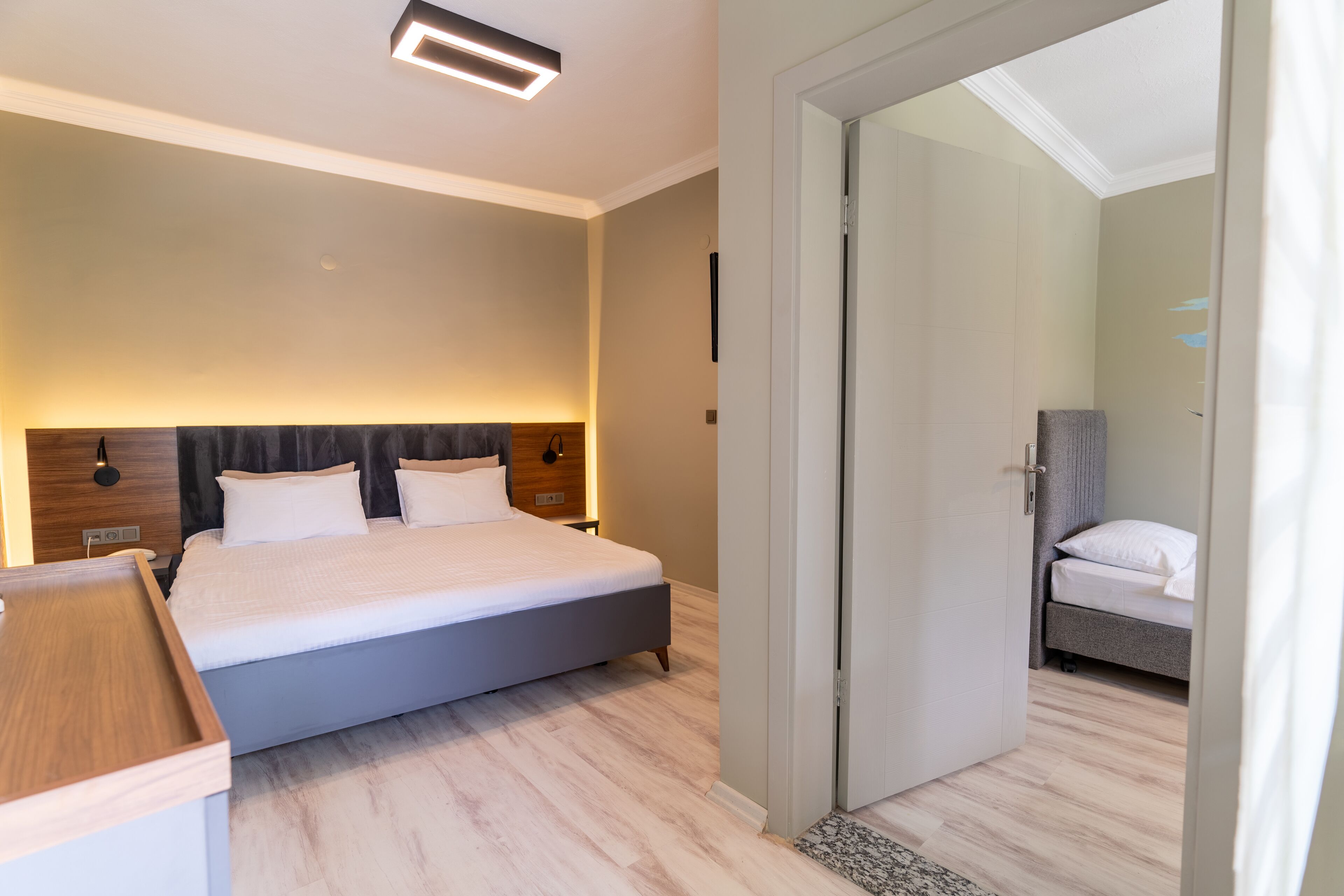 A modern hotel room with a large bed, bedside tables, and a walk-in closet.