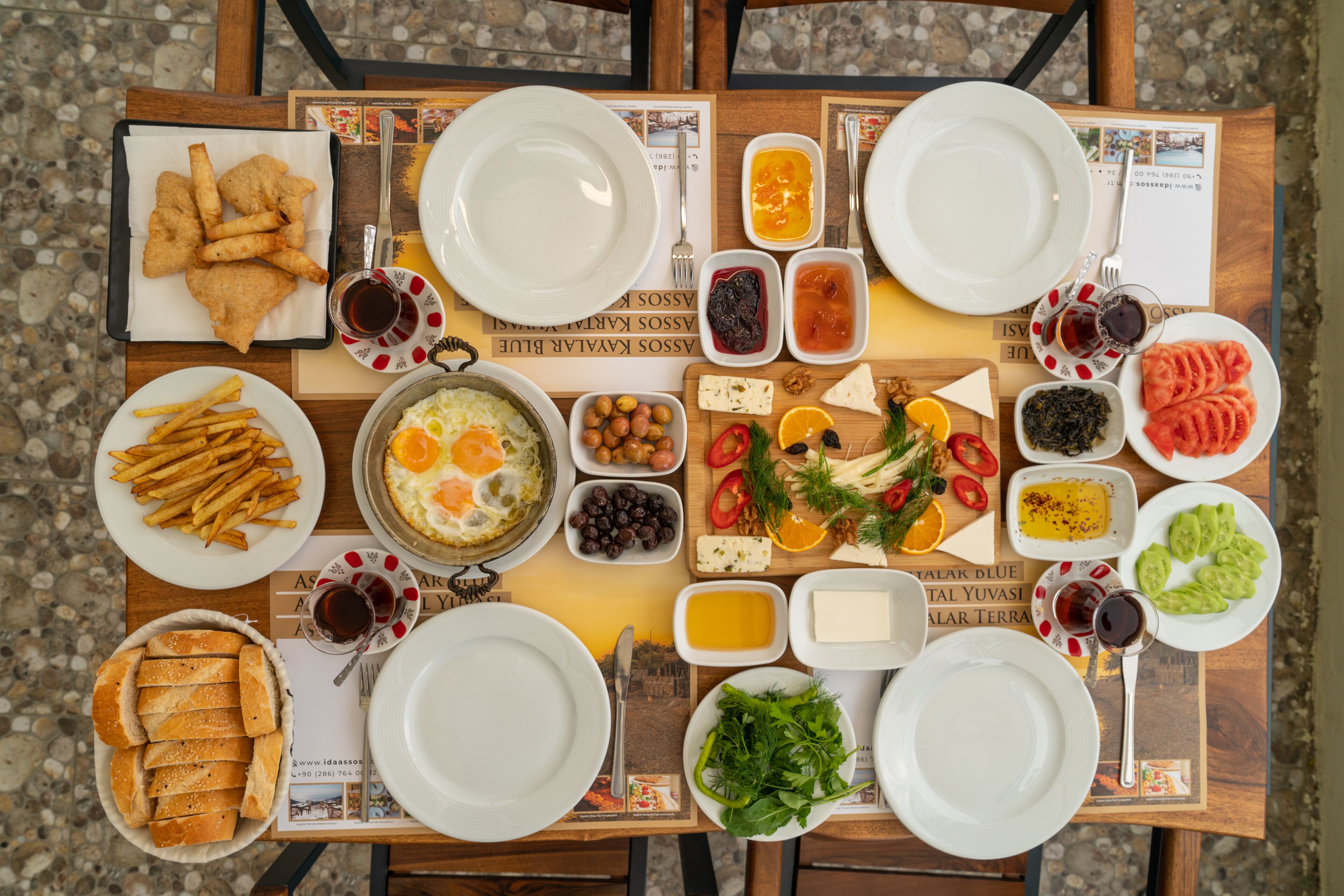 A breakfast table with various food items, plates, and cutlery.